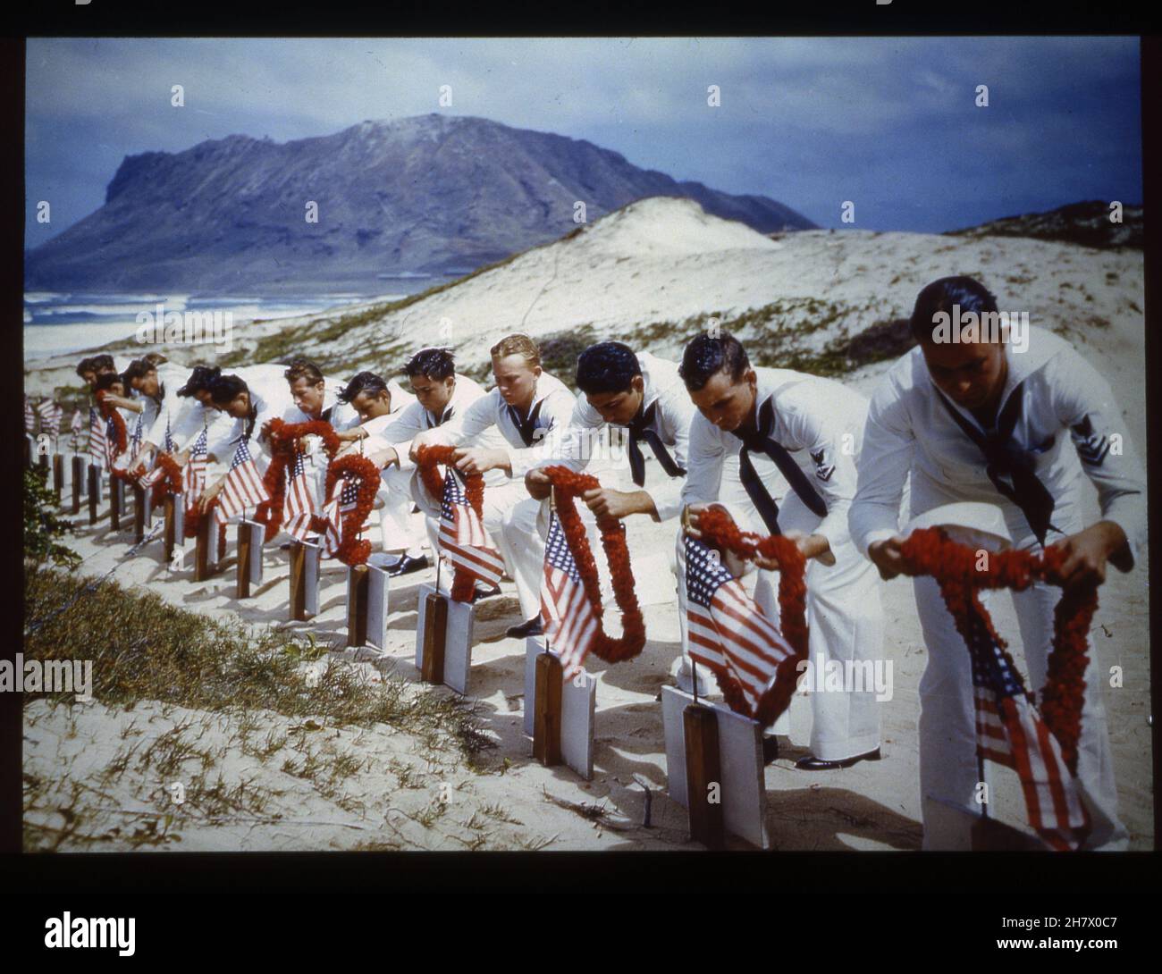 Hawaiian Islands, Spring 1942 -- Original Caption - 'In Hawaiian tradition, sailors pay tribute to casualties of the Pearl Harbor attack at a Hawaiian Islands cemetery, circa Spring 1942. Possibly taken on Memorial Day.' Photo by US Navy Stock Photo