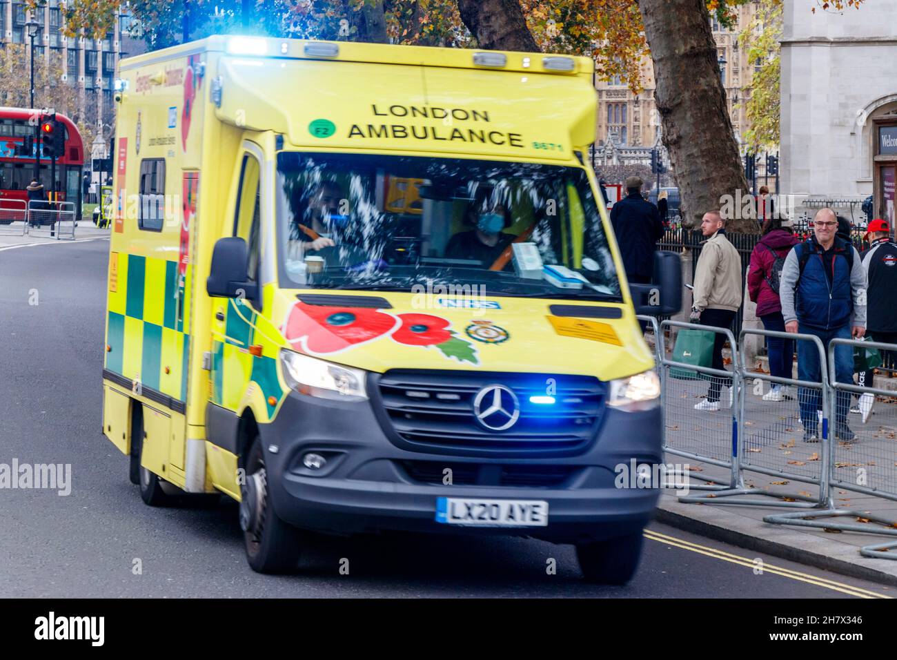 Pedestrians watch a speeding ambulance pass by with blue lights flashing, Westminster, London, UK Stock Photo