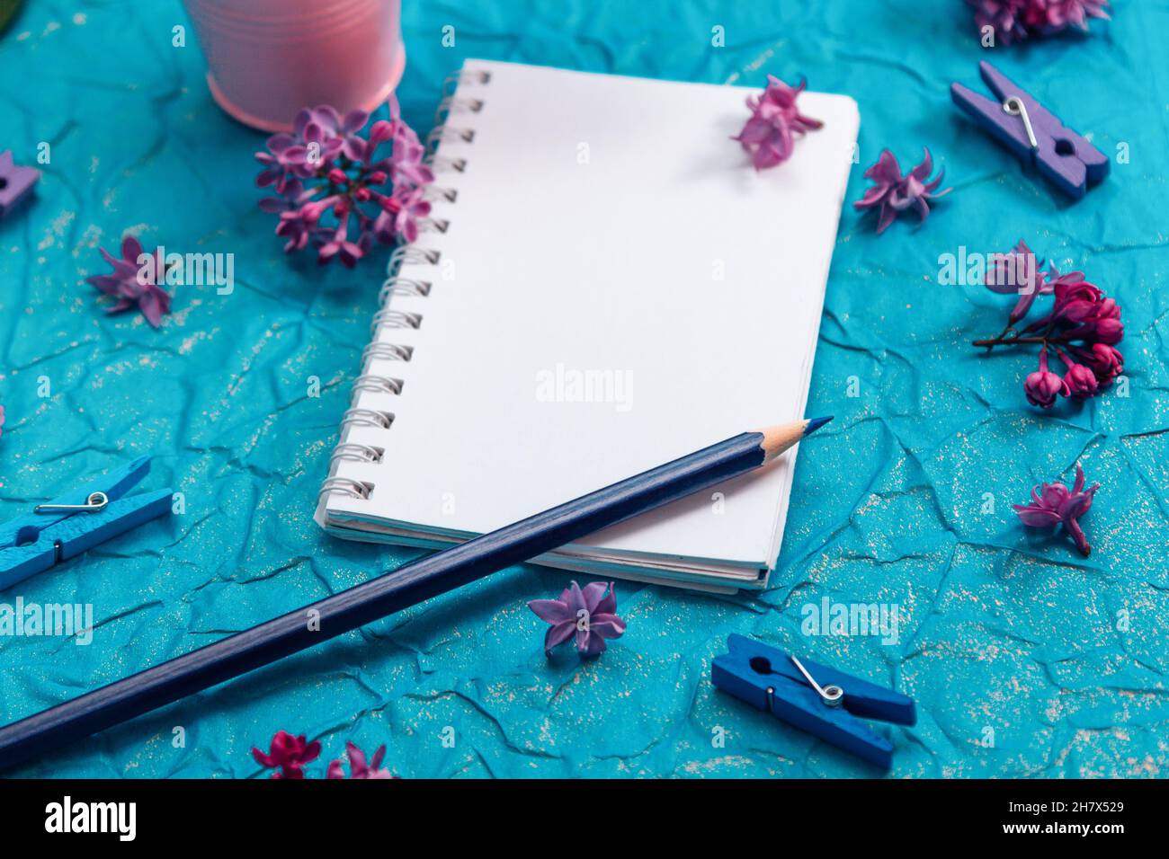 Blank notebook, pencil and lilac flowers on vintage painted blue cardboard background Stock Photo