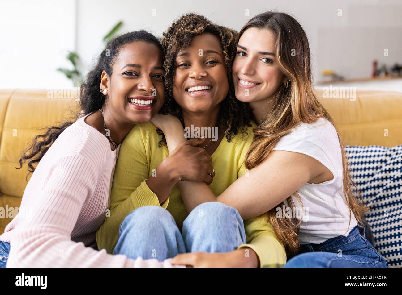 Three united beautiful smiling women sitting together on couch Stock Photo
