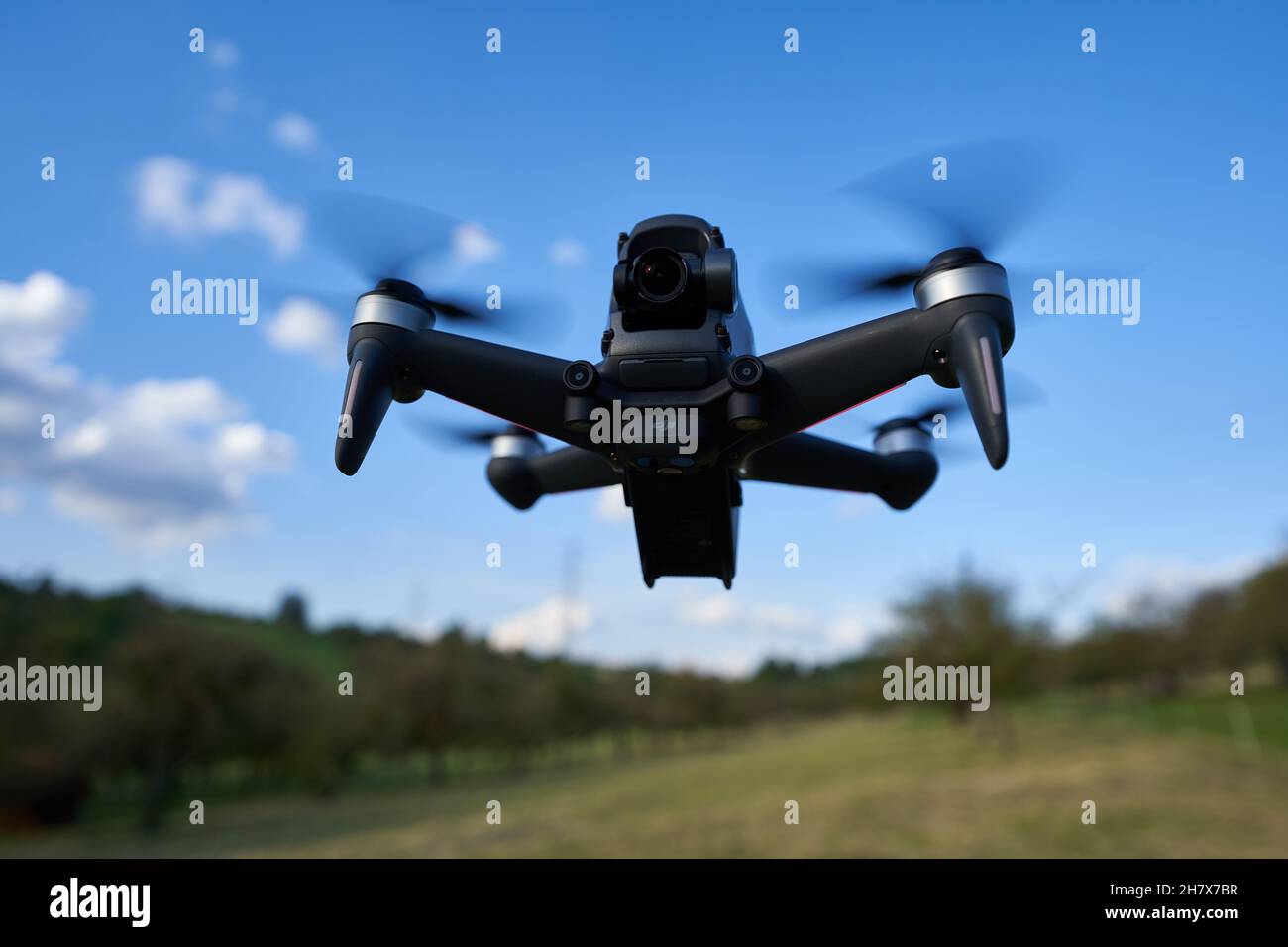 Nürtingen, Germany - June 26, 2021: Dji fpv drone flying over the mowed pasture. Black flying object with the latest technology. Up view. Stock Photo