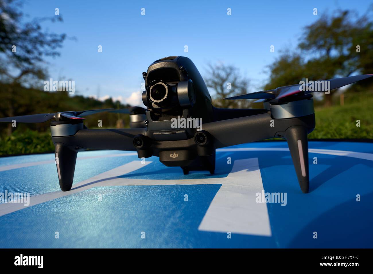 Nürtingen, Germany - June 26, 2021: Dji fpv drone on a blue launch pad. Trees and meadow in the background. Front view. Stock Photo