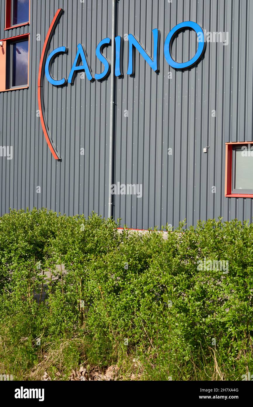 Donzdorf, Germany - May 23, 2021: Blue aristo casino letters on gray building with 3 windows on the facade. Green bushes in the foreground. View from Stock Photo