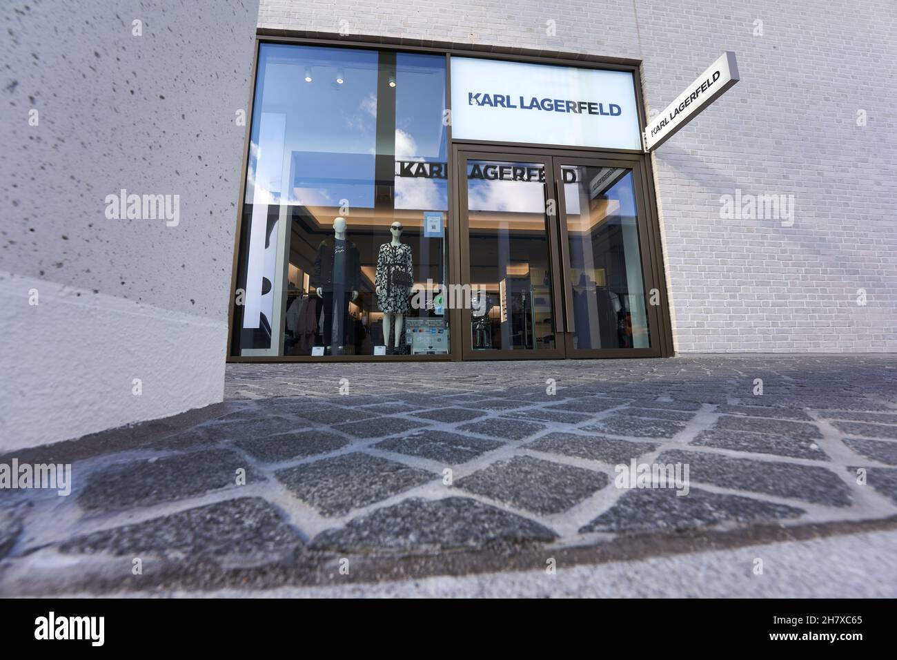 https://c8.alamy.com/comp/2H7XC65/metzingen-germany-march-20-2021-karl-lagerfeld-outlet-store-bright-exterior-facade-cobblestone-in-the-foreground-up-view-wide-angle-2H7XC65.jpg