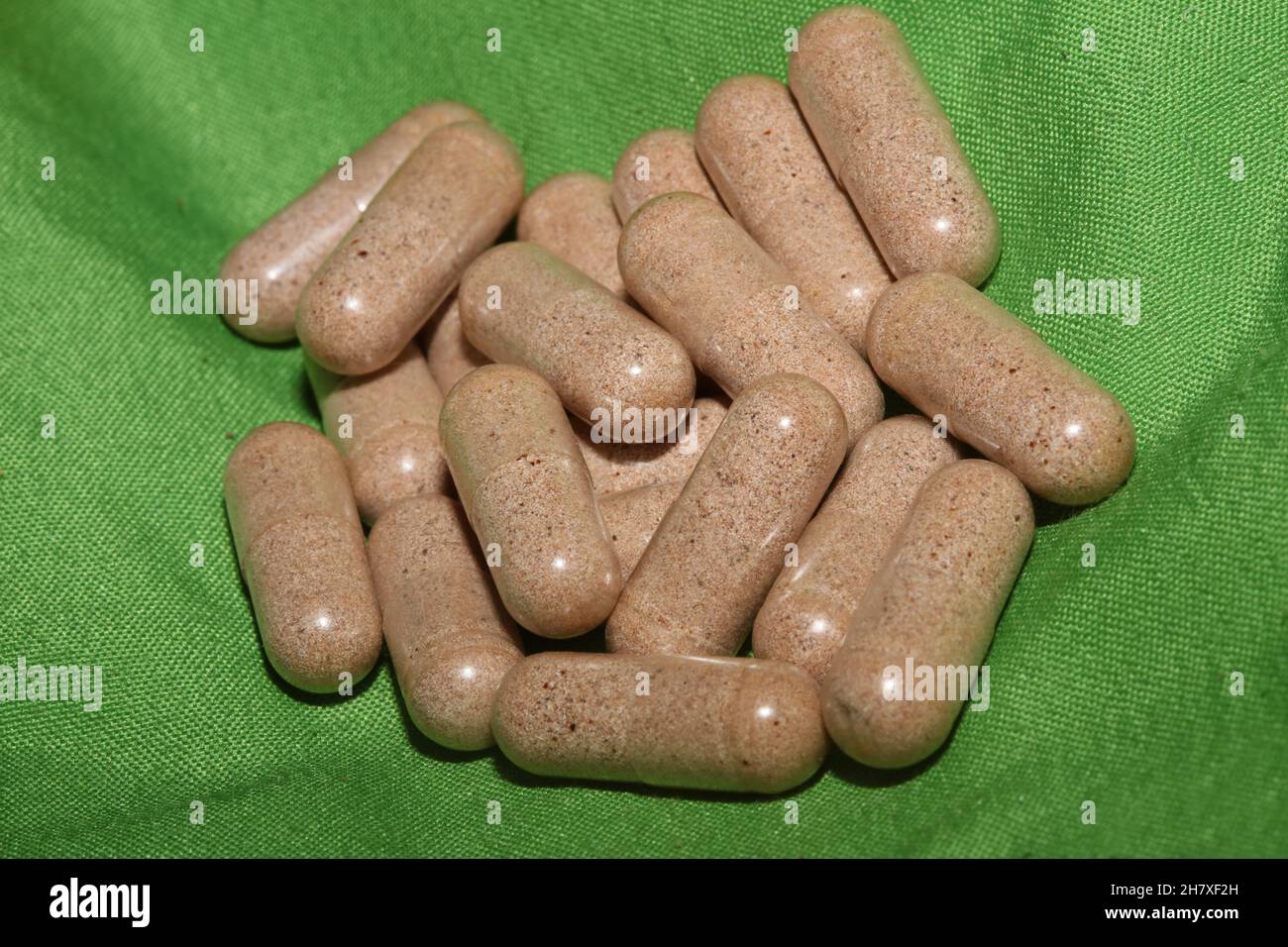 Transparent capsules filled with brown vitamins powder close up