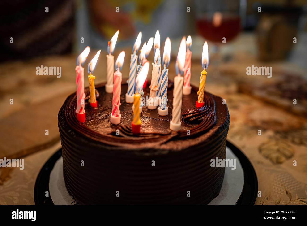 Macro closeup of chocolate buttercream layer small cake with frosting and colorful pink blue and illuminated yellow birthday candles at party birthday Stock Photo