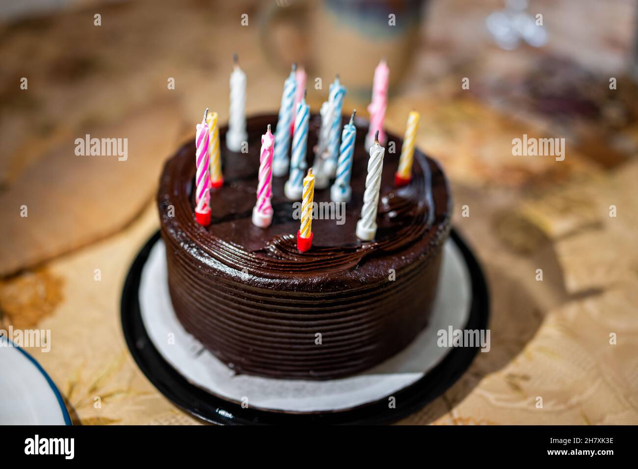 Closeup of homemade chocolate buttercream layer small cake with frosting and colorful pink blue and yellow birthday candles at party birthday celebrat Stock Photo
