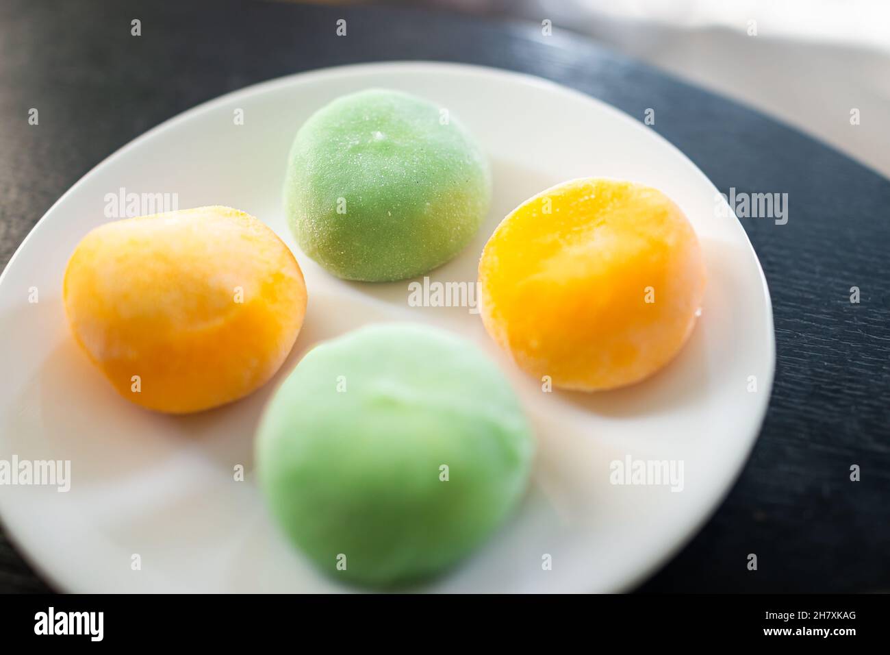 Macro closeup of white plate with four frozen ice cream filled mochi rice cake Japanese dessert