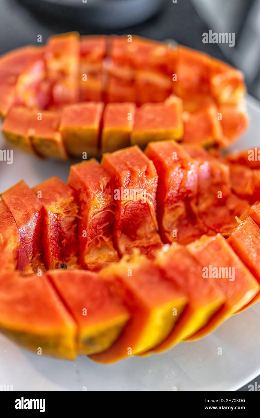 Closeup macro of Caribbean red ripe papaya fruit sliced two halves with fresh orange flesh on slices cut in half vertical view Stock Photo