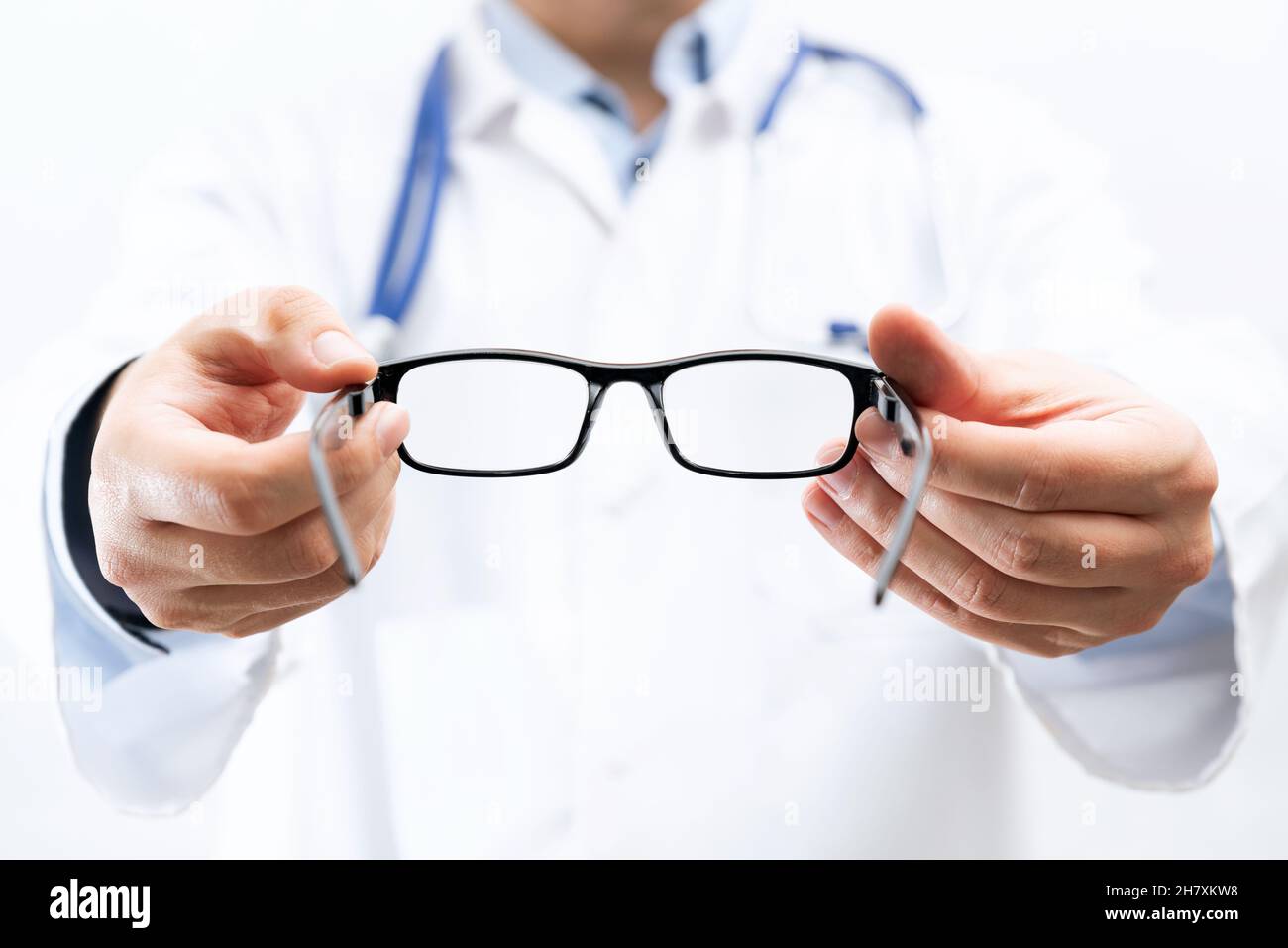 Eye doctor, oculist in clinic. Optometrist holds glasses to try on Stock Photo