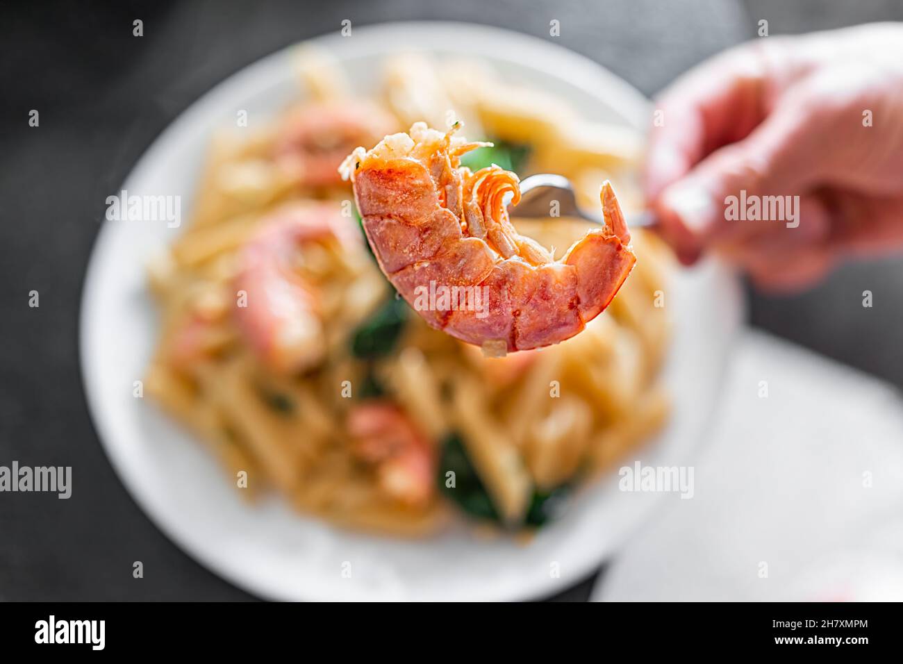 Macro closeup of hand holding fork sticking in sauteed cooked whole