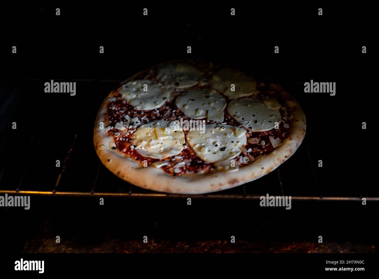 Inside oven with rack and homemade whole pizza mozzarella provolone cheese and sprinkles red