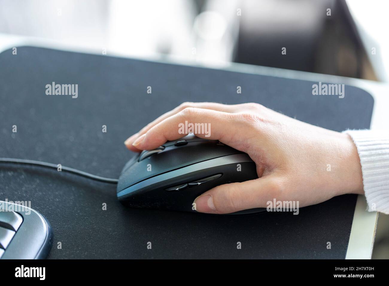 A closeup of a hand holding and using a optical computer mouse to ...