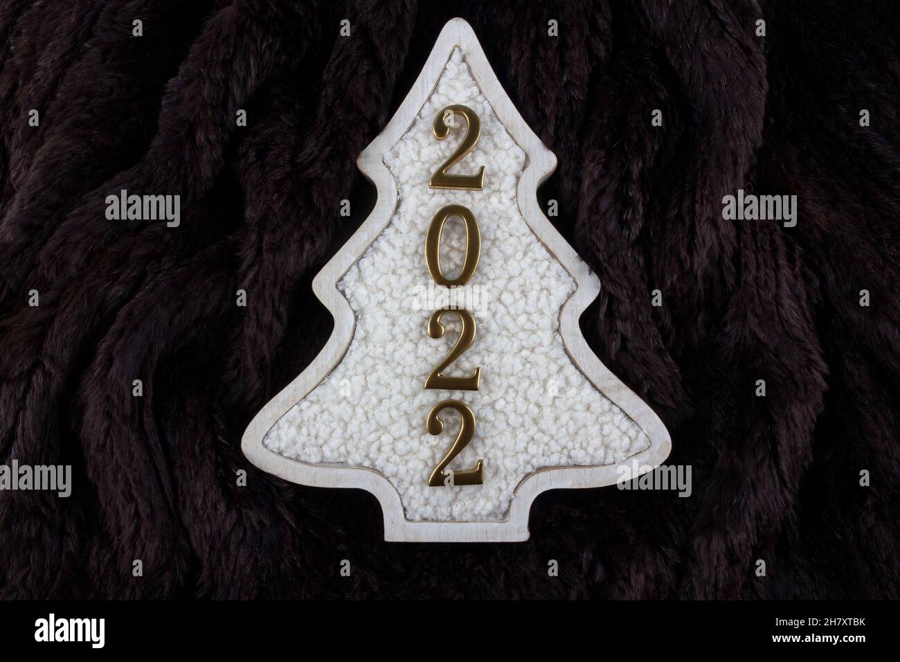 Christmas and 2022 New Year concept. Christmas tree decoration is made from wool on the brown fur background. Flat lay. Copy space. Stock Photo