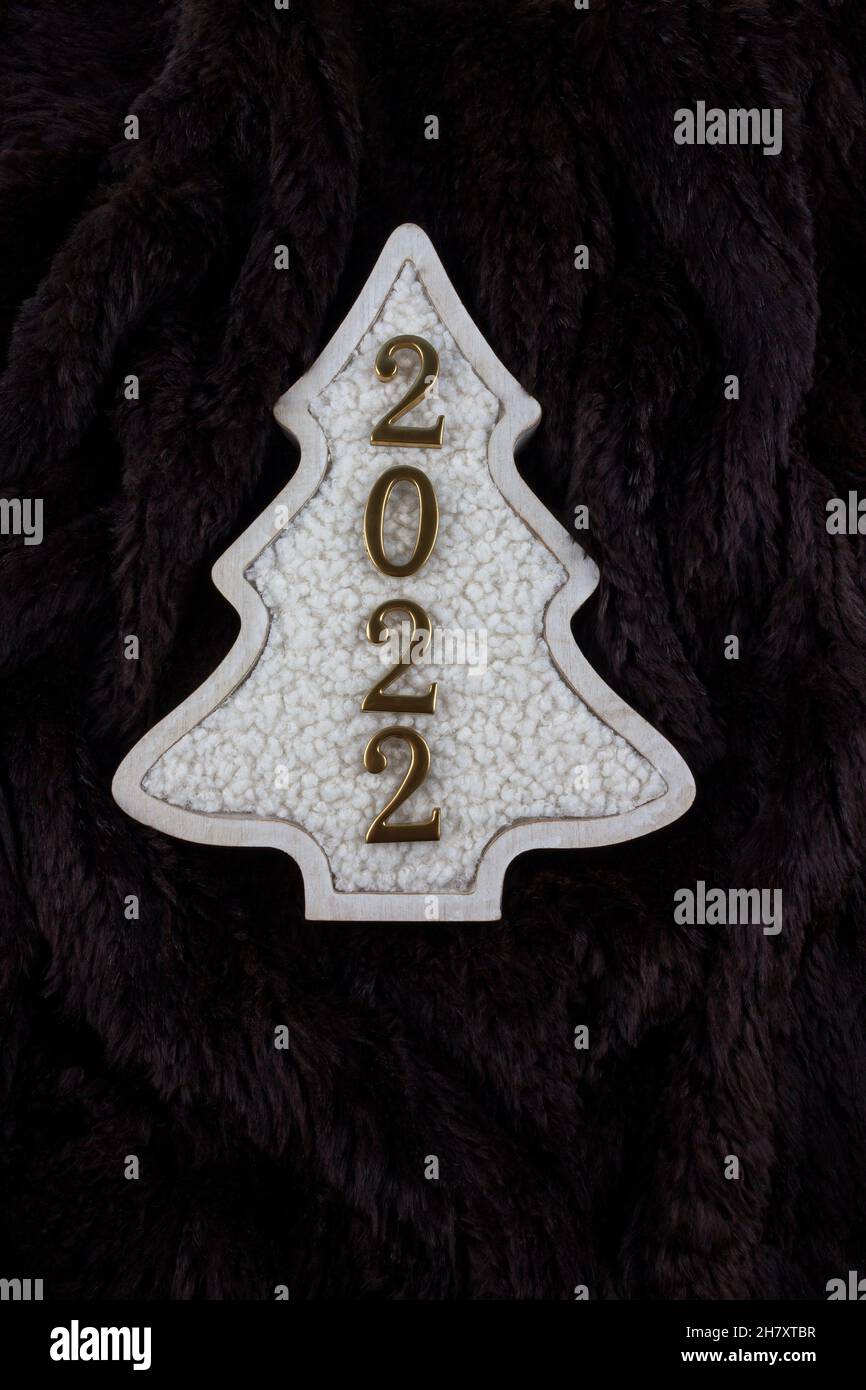 Christmas and 2022 New Year concept. Christmas tree decoration is made from wool on the brown fur background. Flat lay. Copy space. Vertical photo. Stock Photo