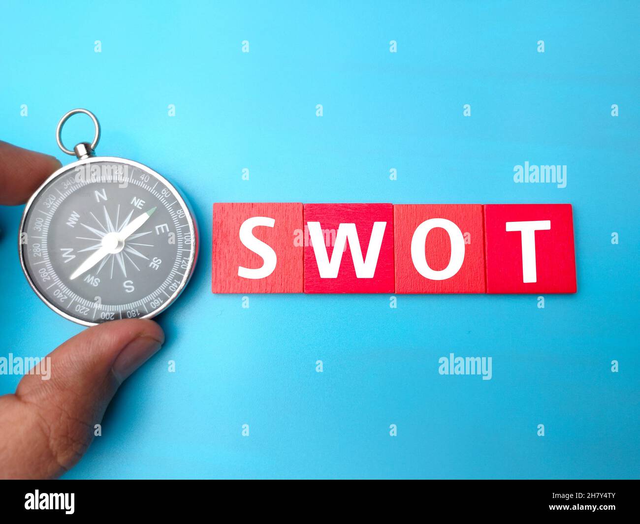 Hand holding compass and SWOT letters Stock Photo