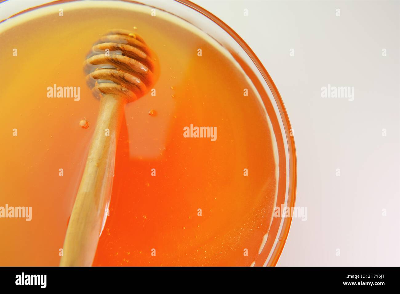 Honey in a transparent glass cup.Healthy natural sweetness. Organic Fresh honey.honey stick . Liquid honey in a jar with dipper. Stock Photo