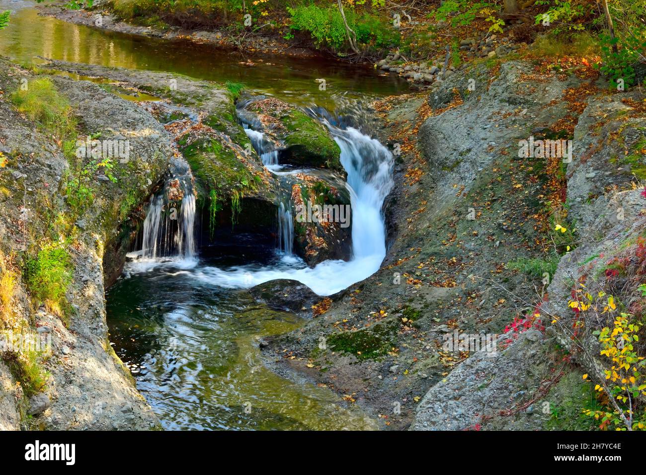 A small waterfall on the Mill Brook with fallen leaves and fall colors at Waterford New Brunswick Canada Stock Photo