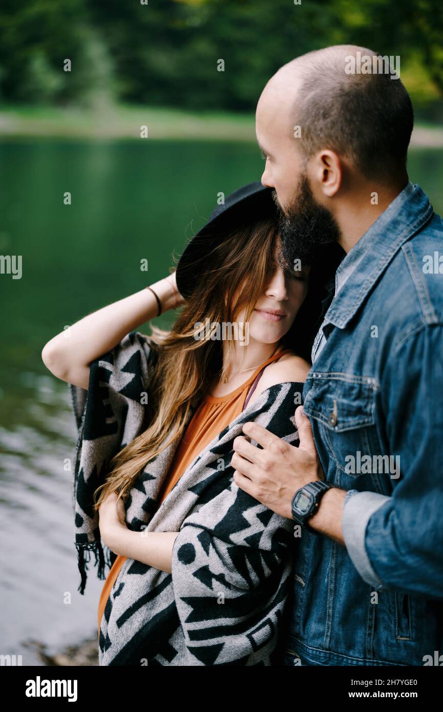 Man hugs the shoulders of a pregnant woman near the lake. Portrait ...