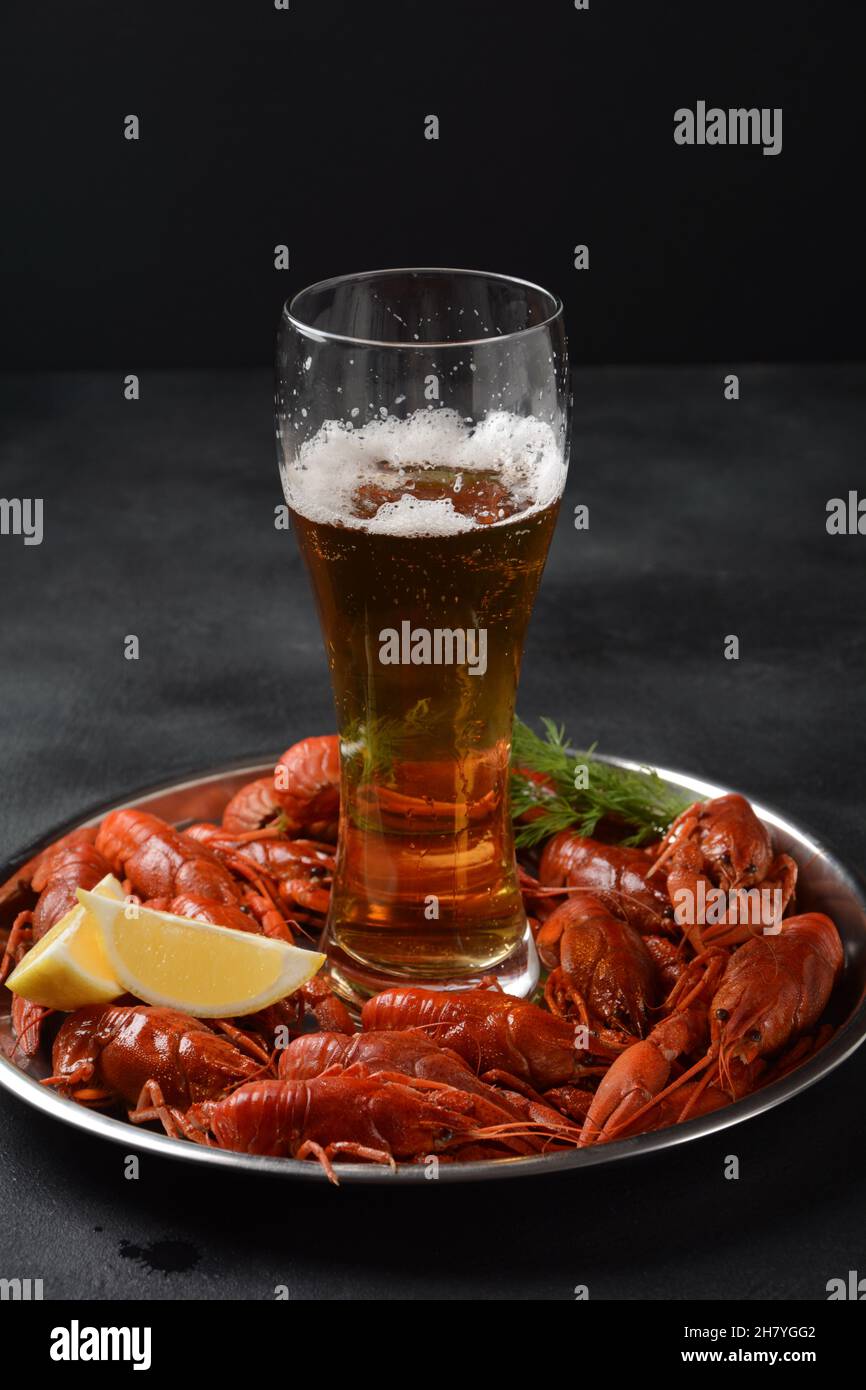 Red boiled crawfishes on table in rustic style. Asian Chinese Food Spicy Crayfish on an iron plate with a mug of beer. Stock Photo
