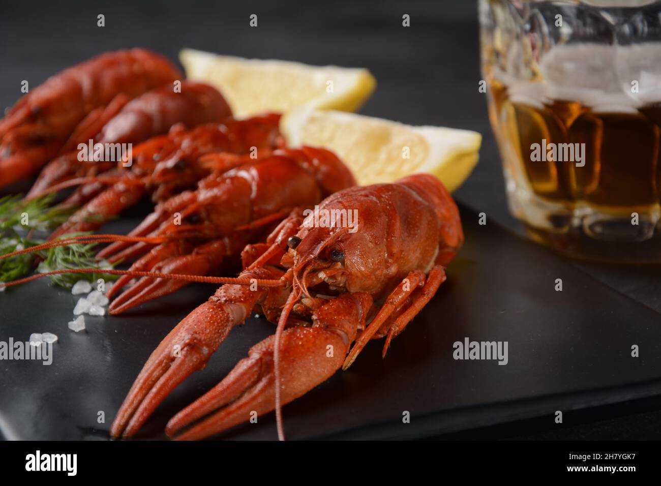 Red boiled crawfishes on table in rustic style. Asian Chinese Food Spicy Crayfish with a mug of beer. Stock Photo
