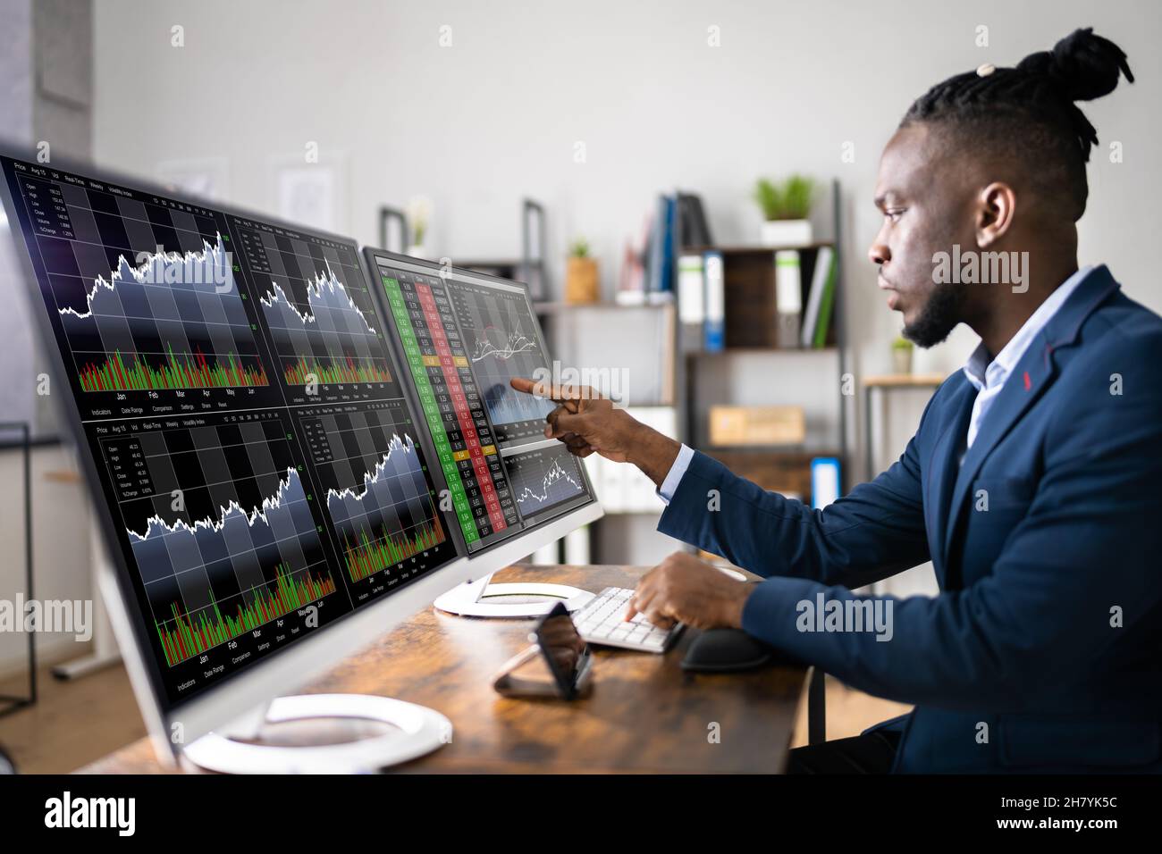 Stock Market Analyst At Office Desk Using Multiple Screens Stock Photo