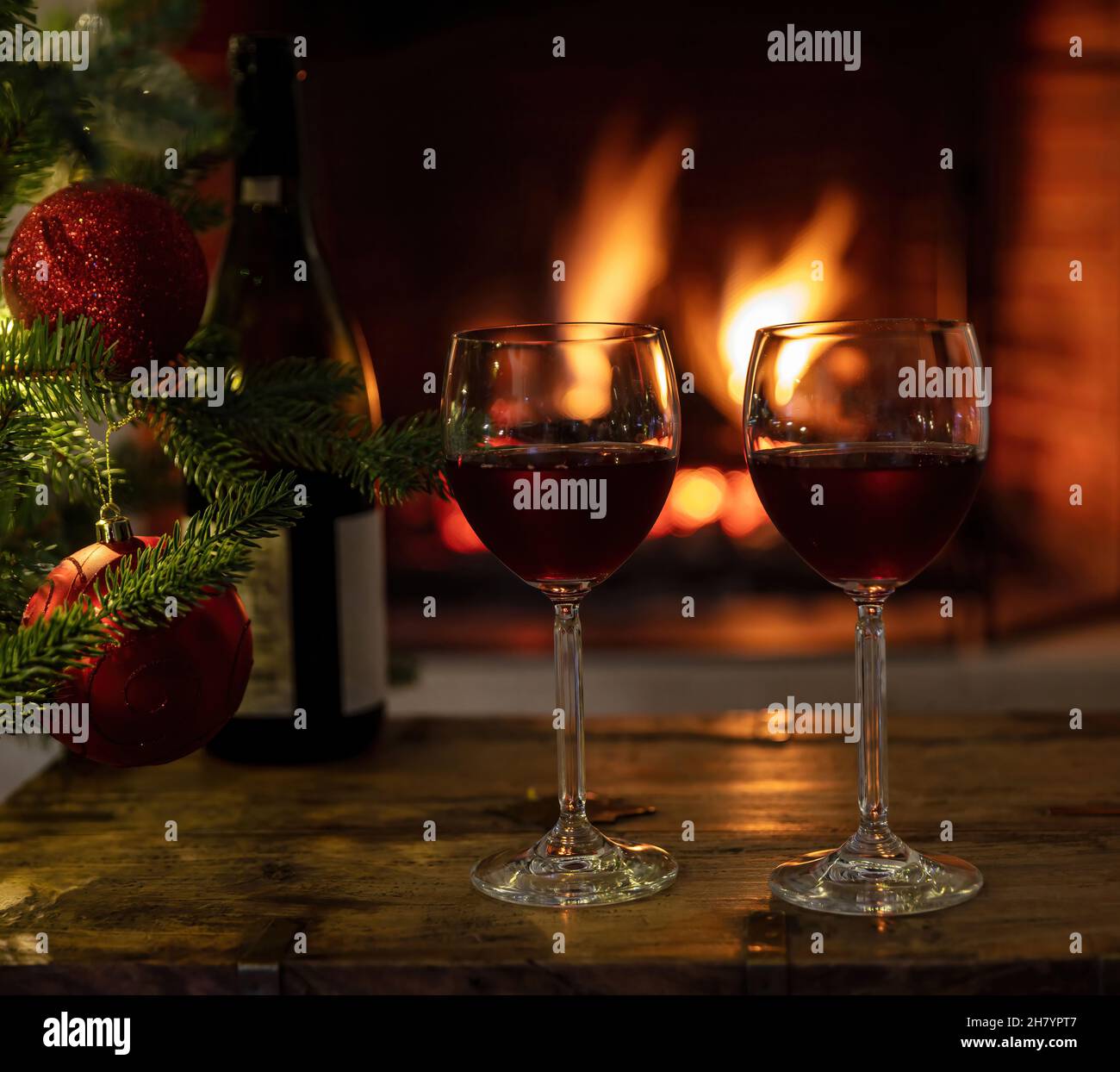 Mulled wine glasses on table in front of burning fireplace. Stock