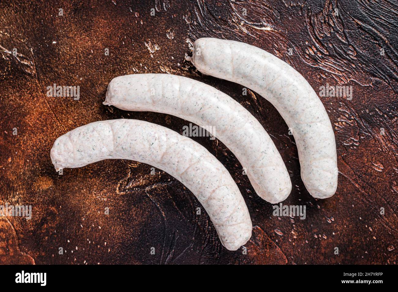Raw German white sausage weisswurst on kitchen table. Dark background. Top view Stock Photo