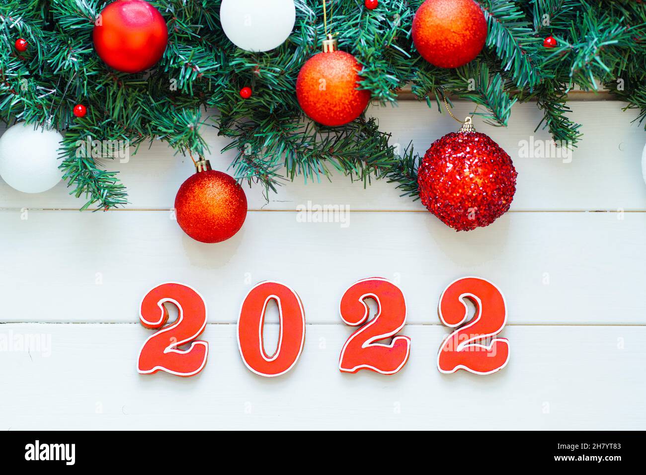 Red numbers 2022 made of ginger bread on white wooden background with decorated Christmas fir branches. Merry Christmas and Happy new year 2022. Top v Stock Photo