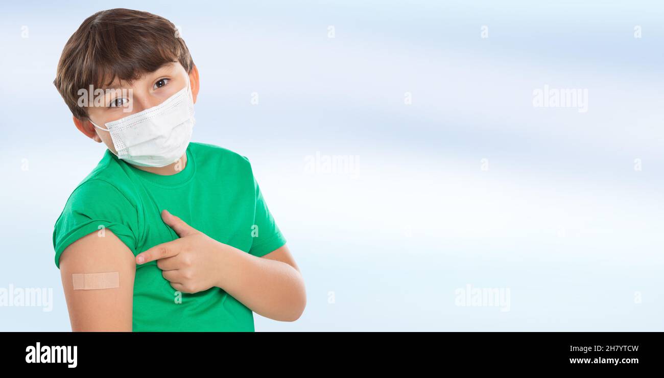 Child kid pointing on plaster after Coronavirus vaccination wearing face mask against Corona Virus COVID-19 Covid copyspace copy space latin Stock Photo