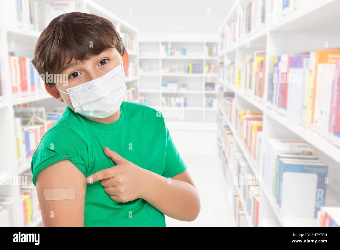 Child kid pointing on plaster after Coronavirus vaccination at school wearing face mask against Corona Virus COVID-19 Covid copyspace copy space latin Stock Photo