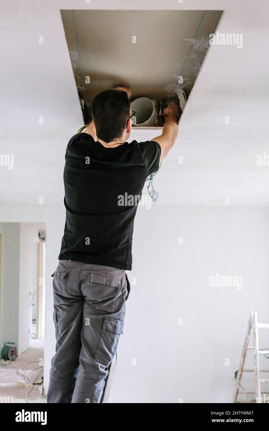 Man preparing extractor hood installation on kitchen ceiling Stock Photo
