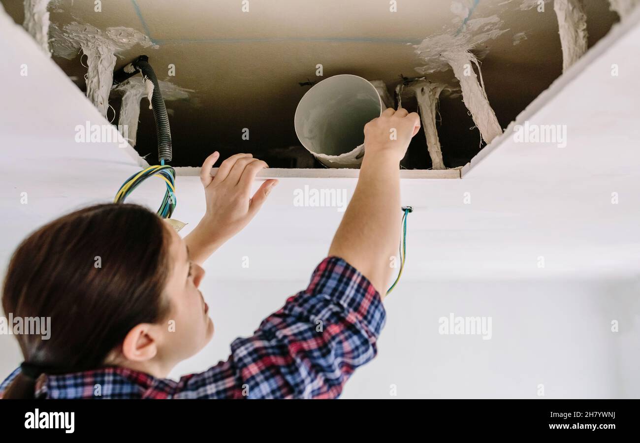 Woman placing tube for kitchen hood installation Stock Photo