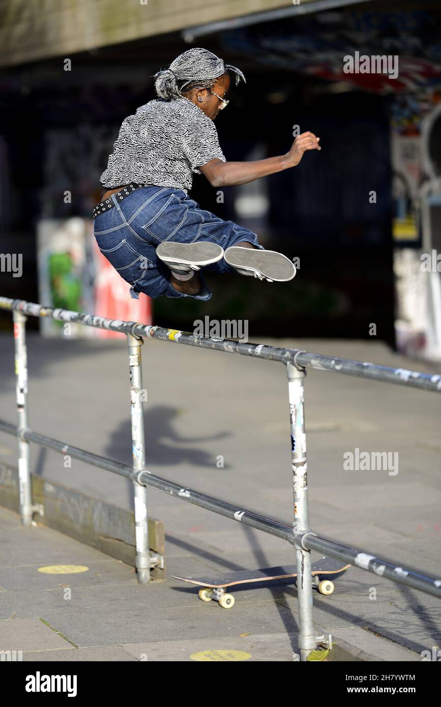 London, England, UK. Skateboarder on the South Bank, jumping over a barrier Stock Photo