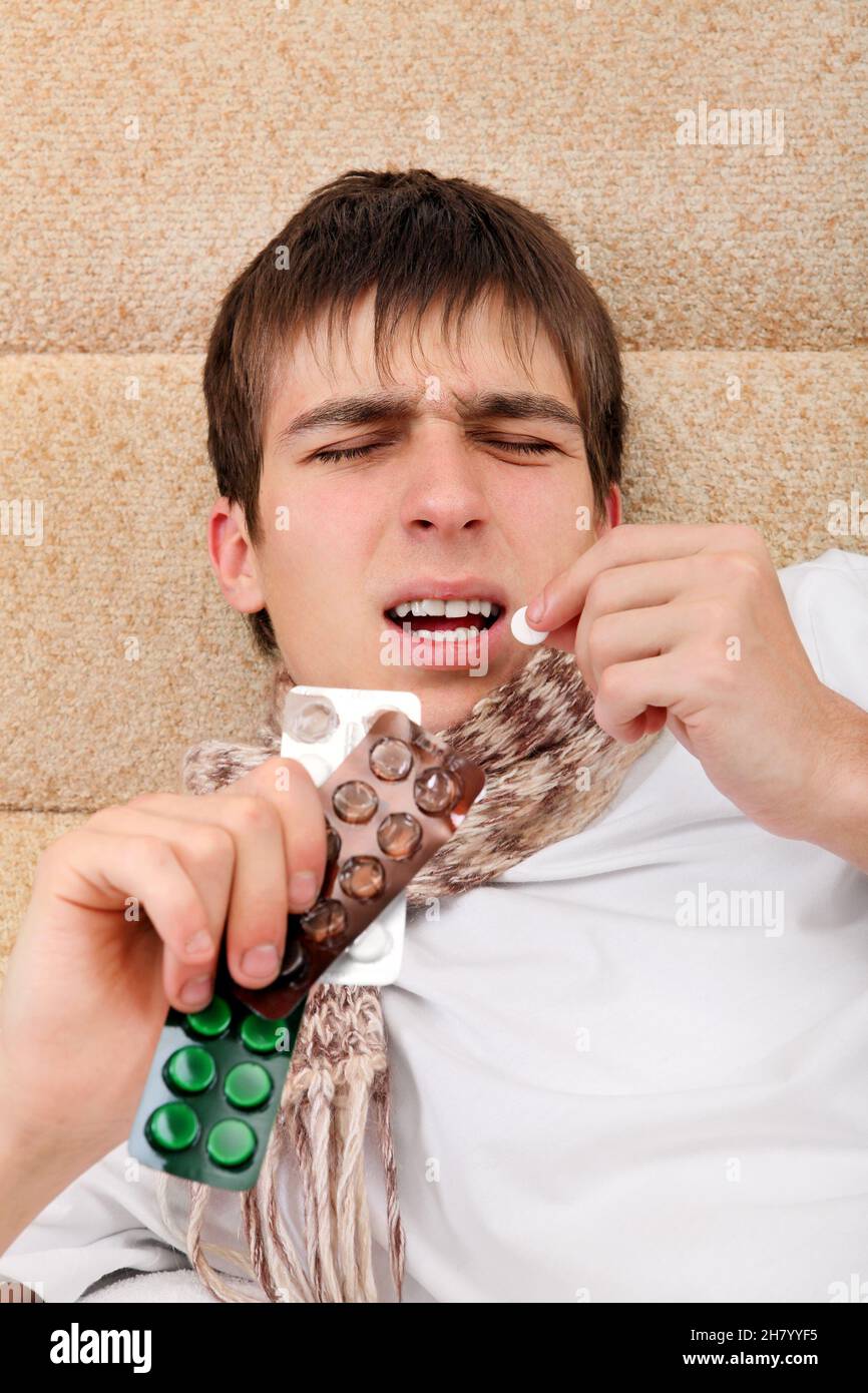 Sick Young Man take a Pill on the Bed at the Home Stock Photo
