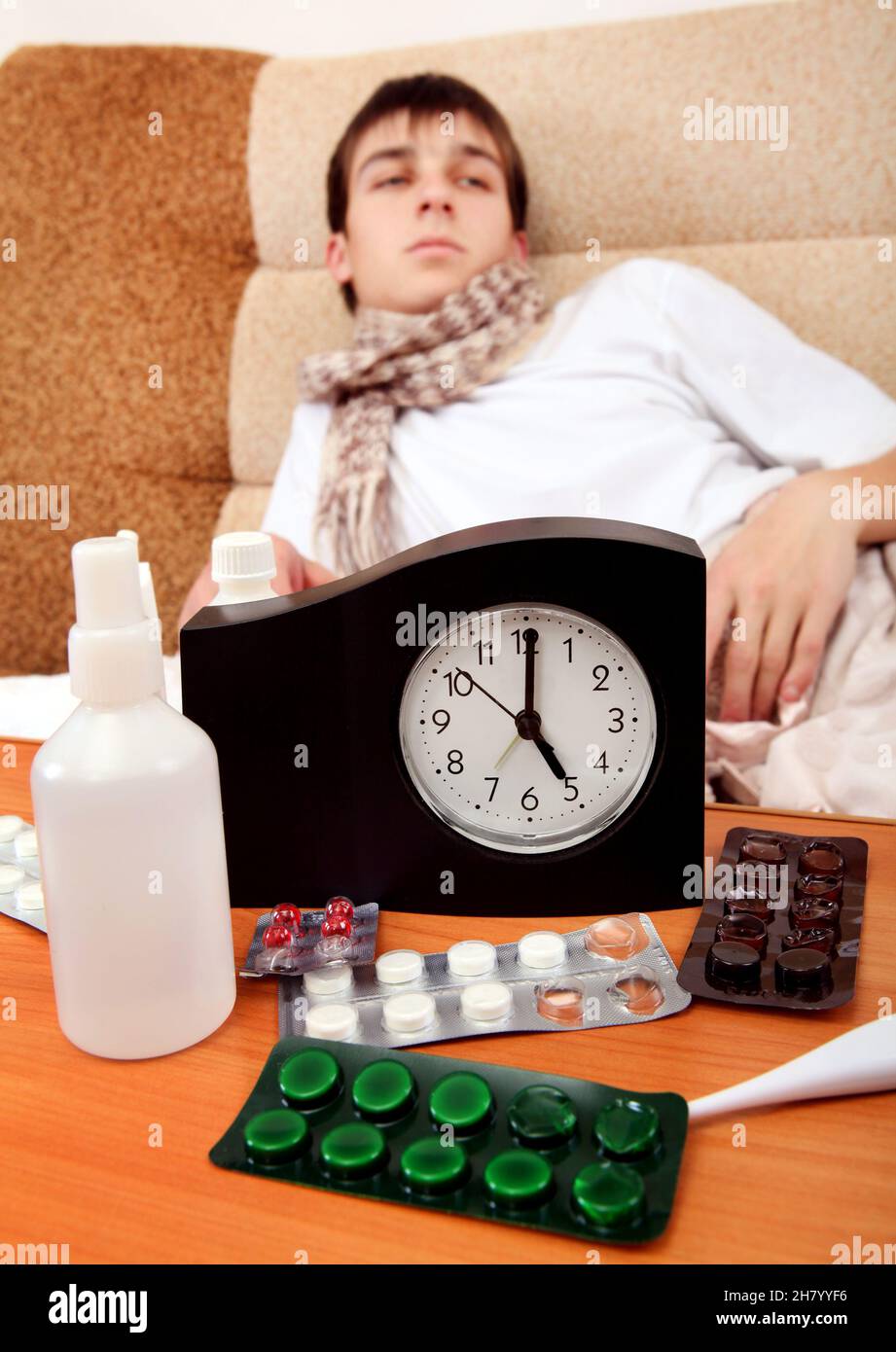 Focus on the Clock. Sick Teenager on the Bed at the Home Stock Photo