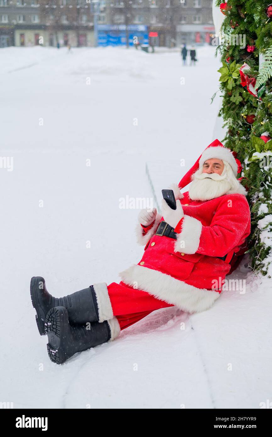 Santa claus using the phone outdoors. Merry Christmas Stock Photo - Alamy