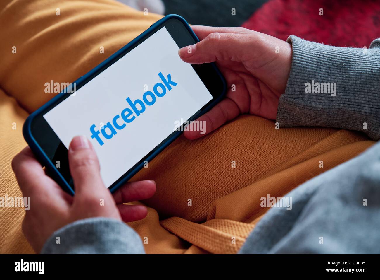 Barcelona, Spain - March 22 2021 : a woman holding an iPhone 12 pro opens Facebook app Stock Photo