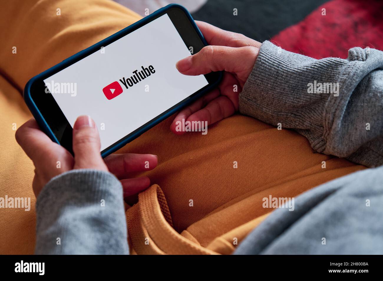 Barcelona, Spain - March 22 2021 : a woman holding an iPhone 12 pro opens youtube app Stock Photo