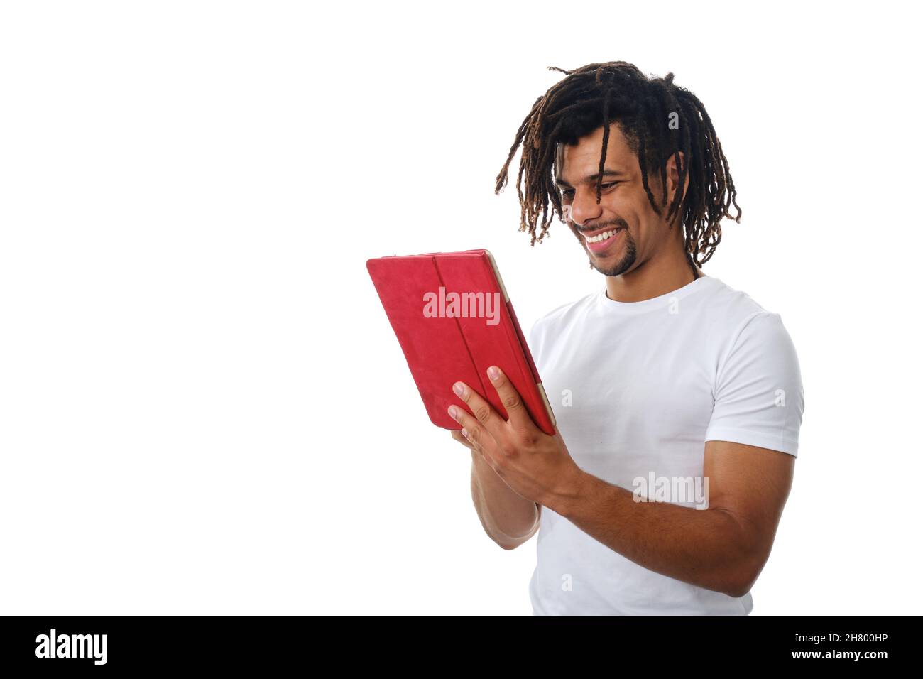 Latin man smiling while using a digital tablet over an isolated background. Stock Photo