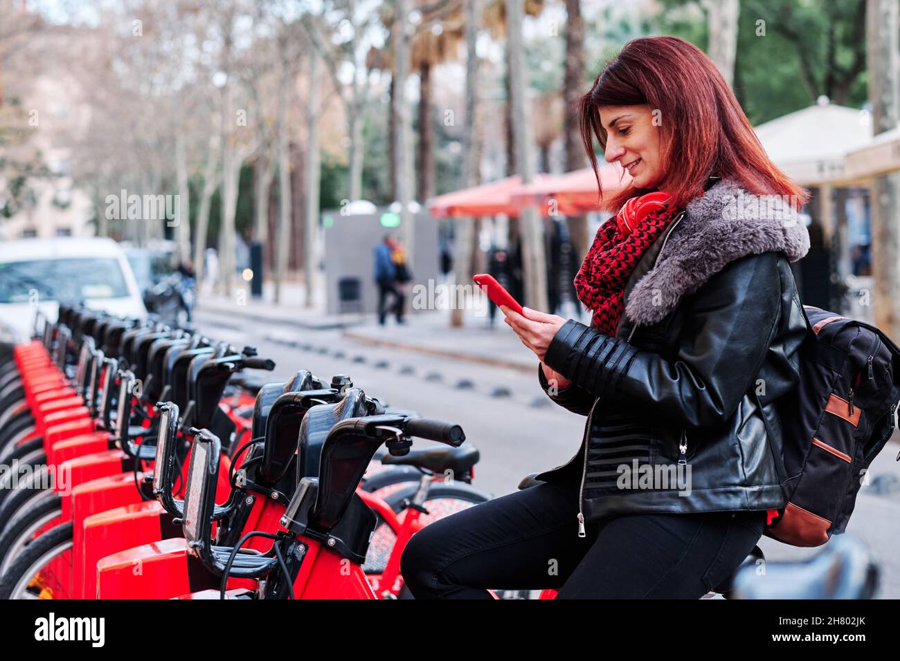 Woman using smartphone in a bike rental station. Stock Photo