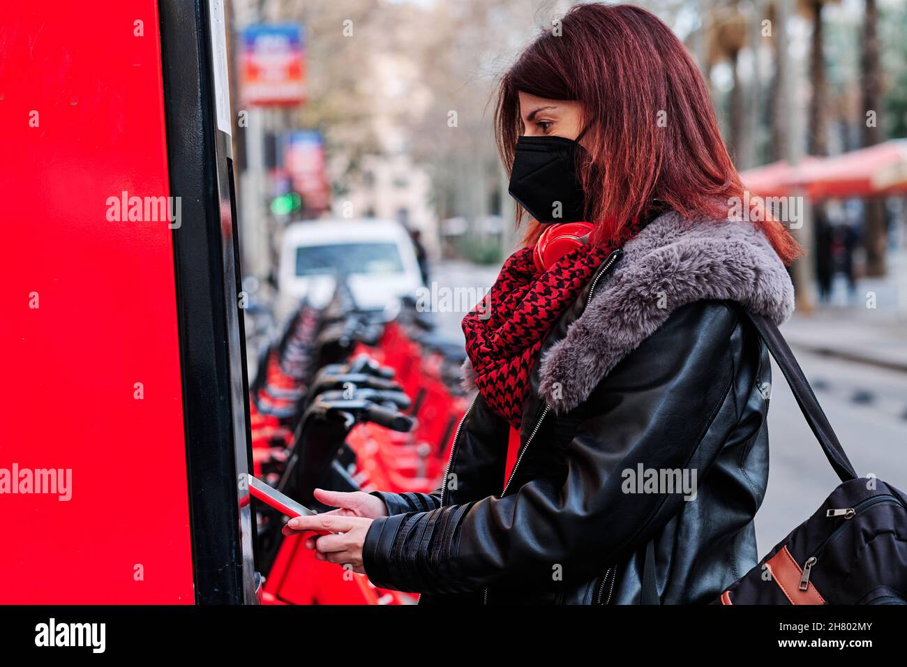 Woman using mobile phone app to rent a bike. Stock Photo