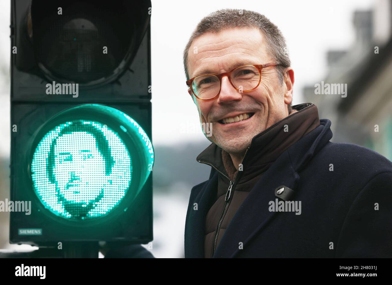 Wuppertal, Germany. 26th Nov, 2021. Uwe Schneidewind (Greens), Lord Mayor of Wuppertal, stands next to a traffic light manikin with the face of Friedrich Engels. On the occasion of the Engels Year, the city has installed the traffic light manikin opposite the Engelshaus at a pedestrian crossing. Friedrich Engels (1820-1895) was born in the Wuppertal district of Barmen and wrote 'The Manifesto of the Communist Party' together with Marx. Credit: Oliver Berg/dpa/Alamy Live News Stock Photo