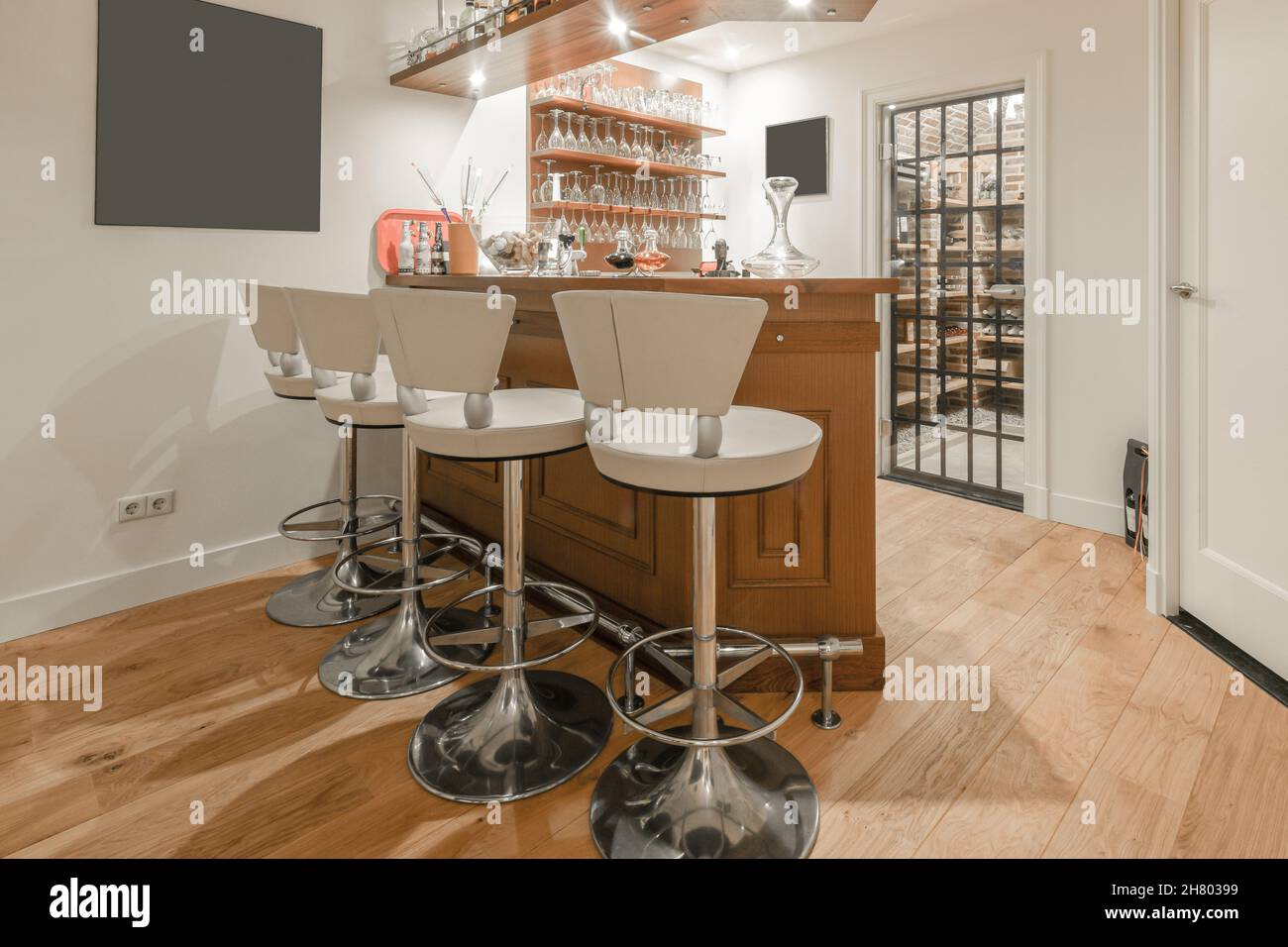 Modern home bar with wooden table and chairs placed near counter with