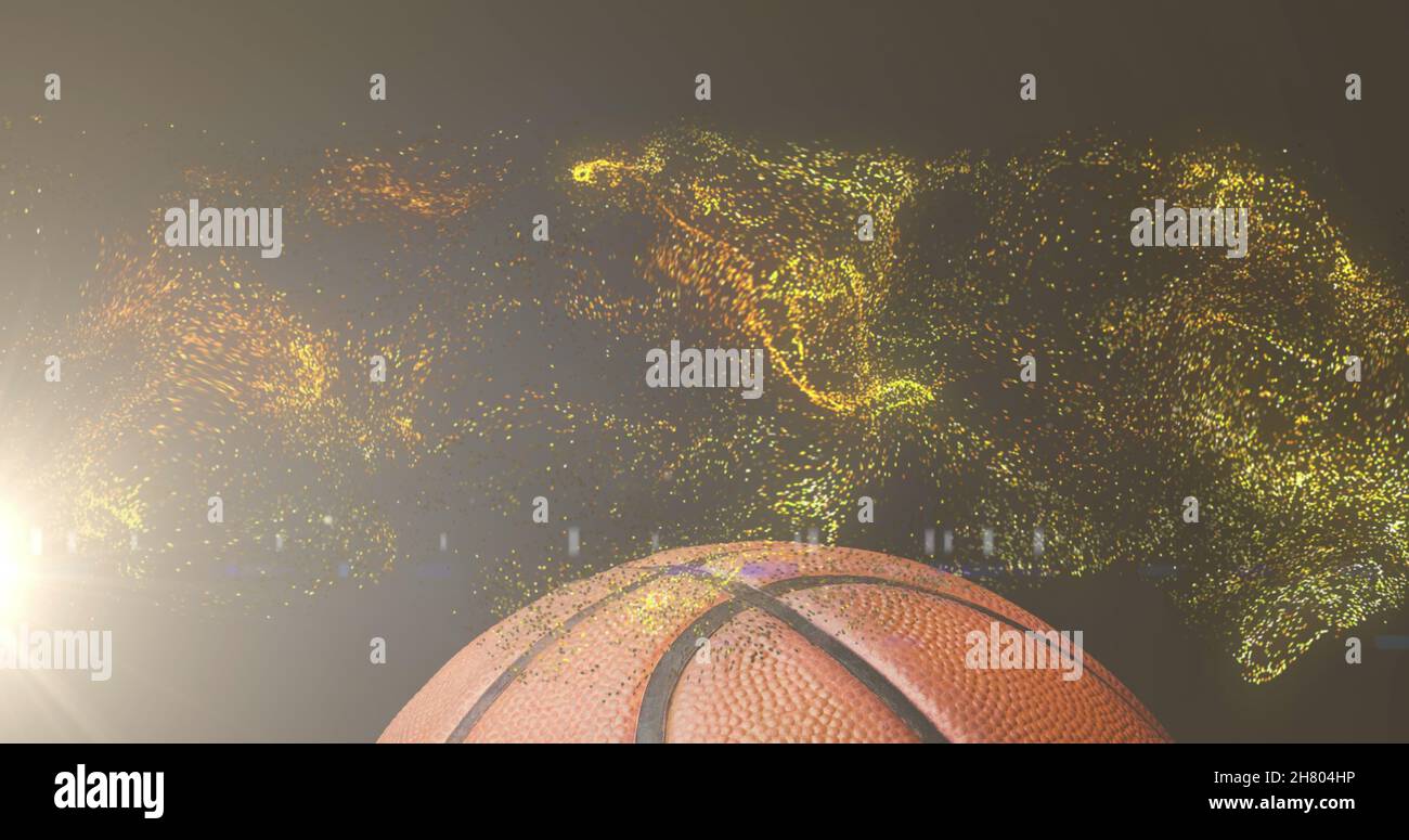 Image of glowing gold particles moving over basketball Stock Photo