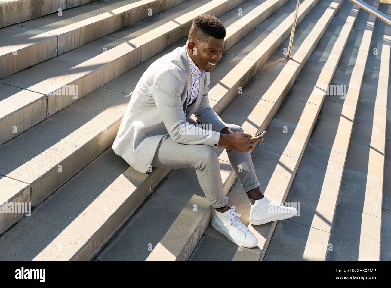 Full body side view of African American male in formal wear sitting on