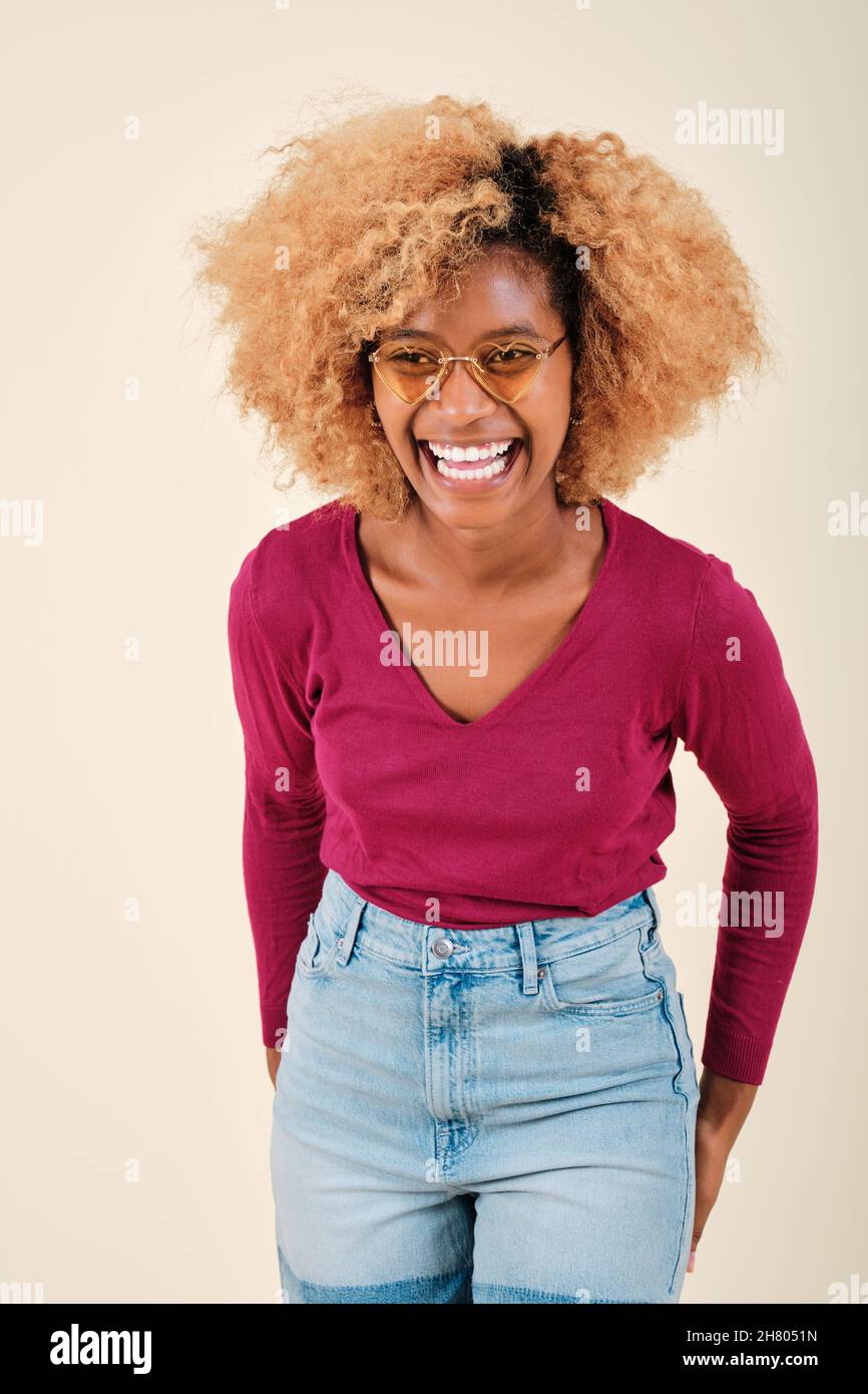 Happy and excited curly haired woman smiling while standing against an isolated background. Stock Photo