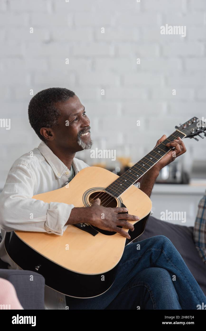 Pleased african american man playing acoustic guitar in nursing home ...