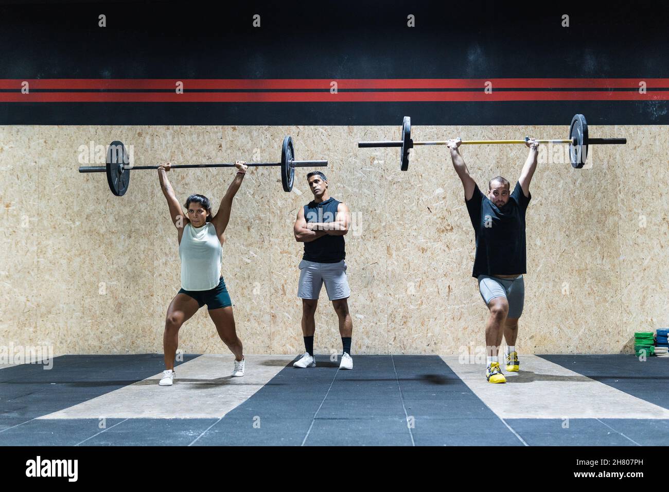 Full body group of strong Hispanic athletes lifting heavy barbells near
