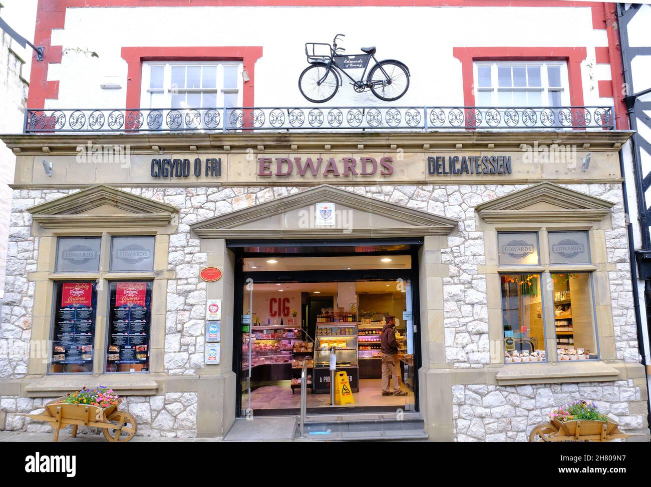 A delicatessan store in Conway town centre with an open doorway and bicycle decorating the facade. Stock Photo